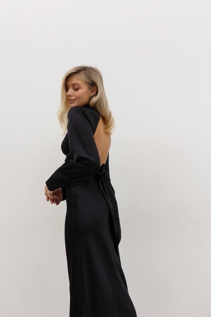 Woman wearing a black open-back dress against a white background