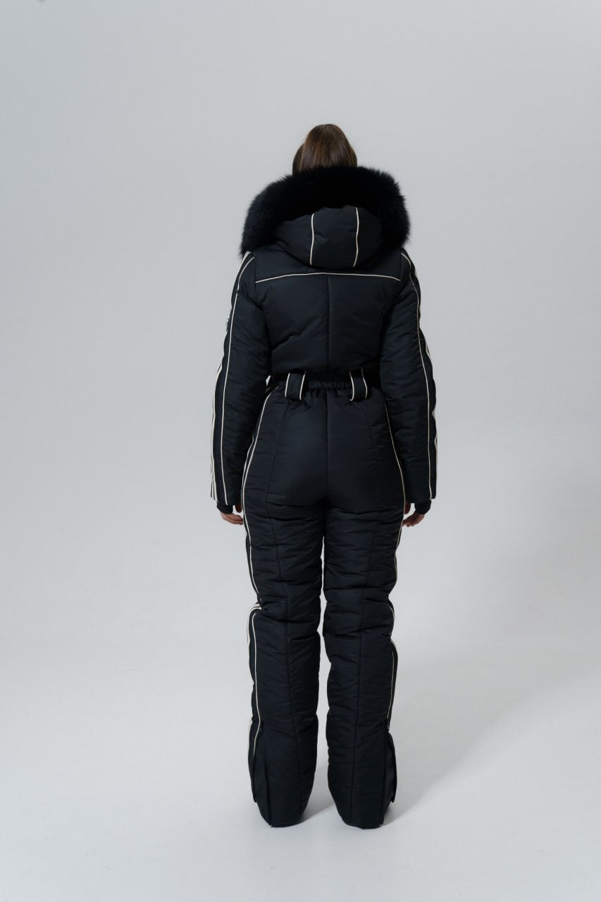 Person wearing a black snowsuit with fur hood on a white background