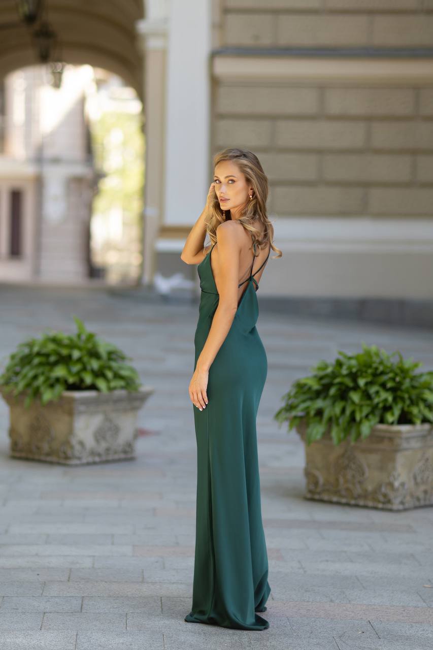 Woman in a green dress standing outdoors with classical architecture in the background