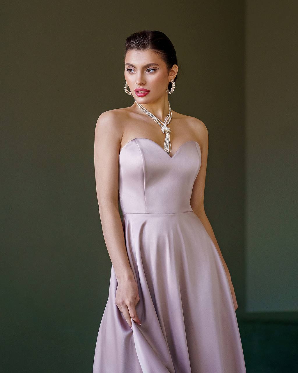Woman wearing a strapless lavender dress with a plain background