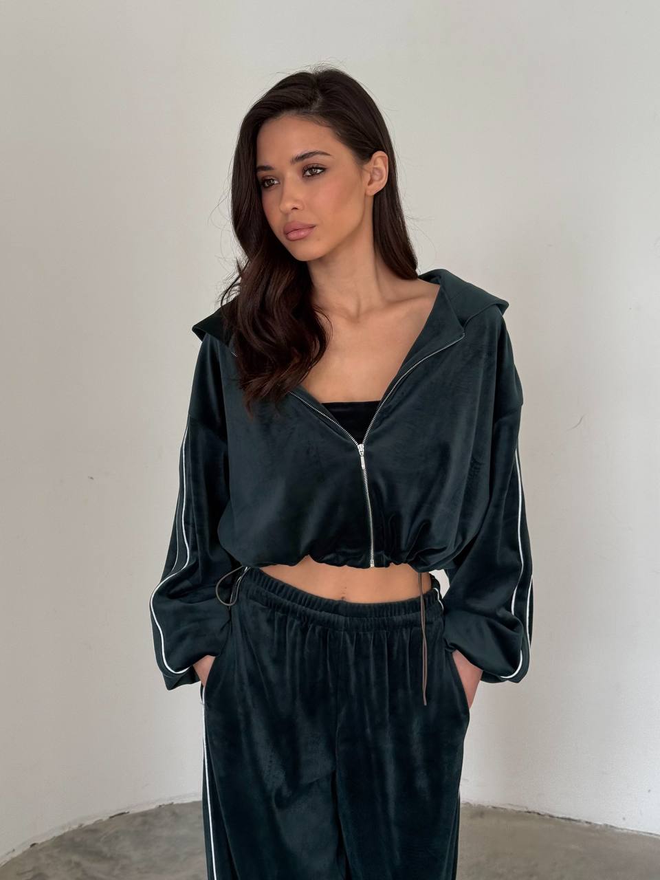Woman wearing a dark green tracksuit against a plain background