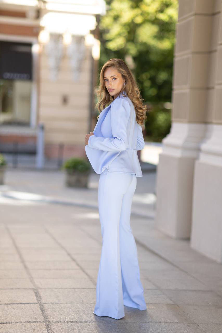 Woman in a light blue outfit standing on a city street.