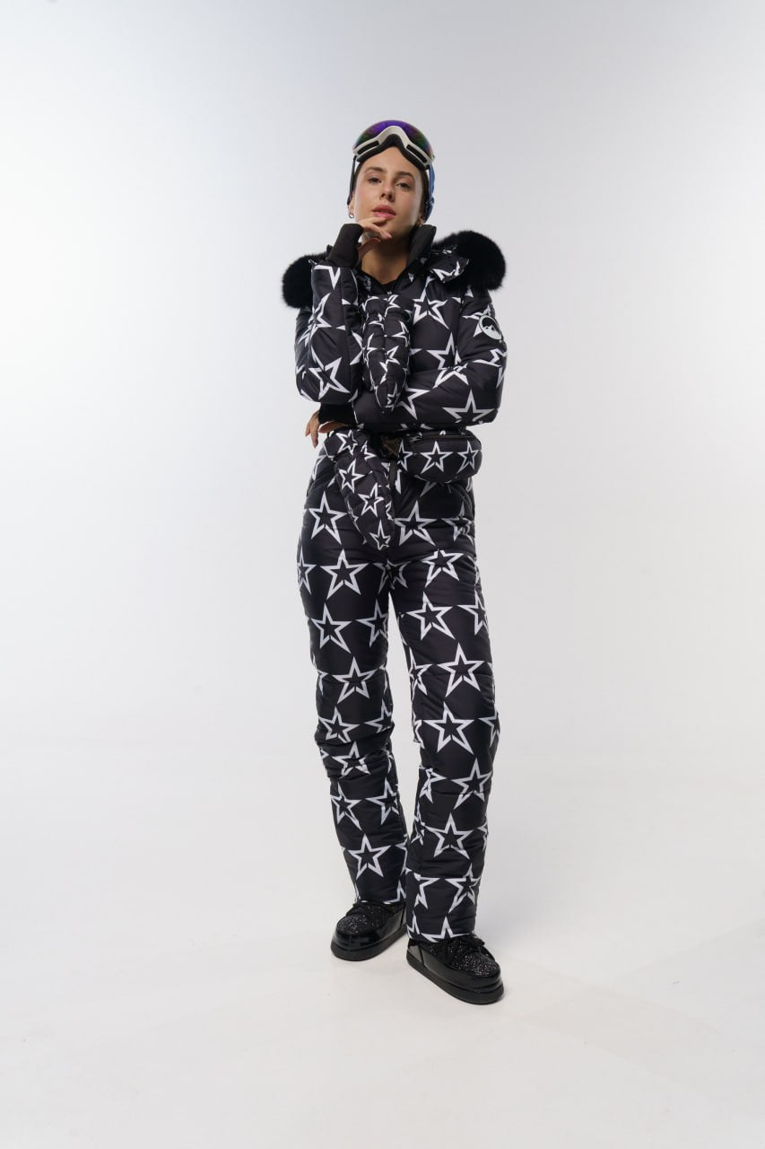 Person wearing a black and white star-patterned onesie with a matching hat on a white background