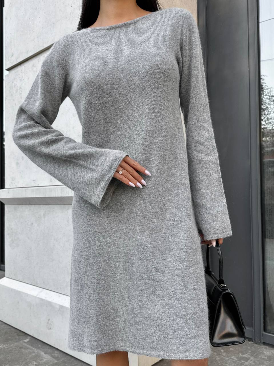 Person wearing a gray dress with long sleeves in an urban setting