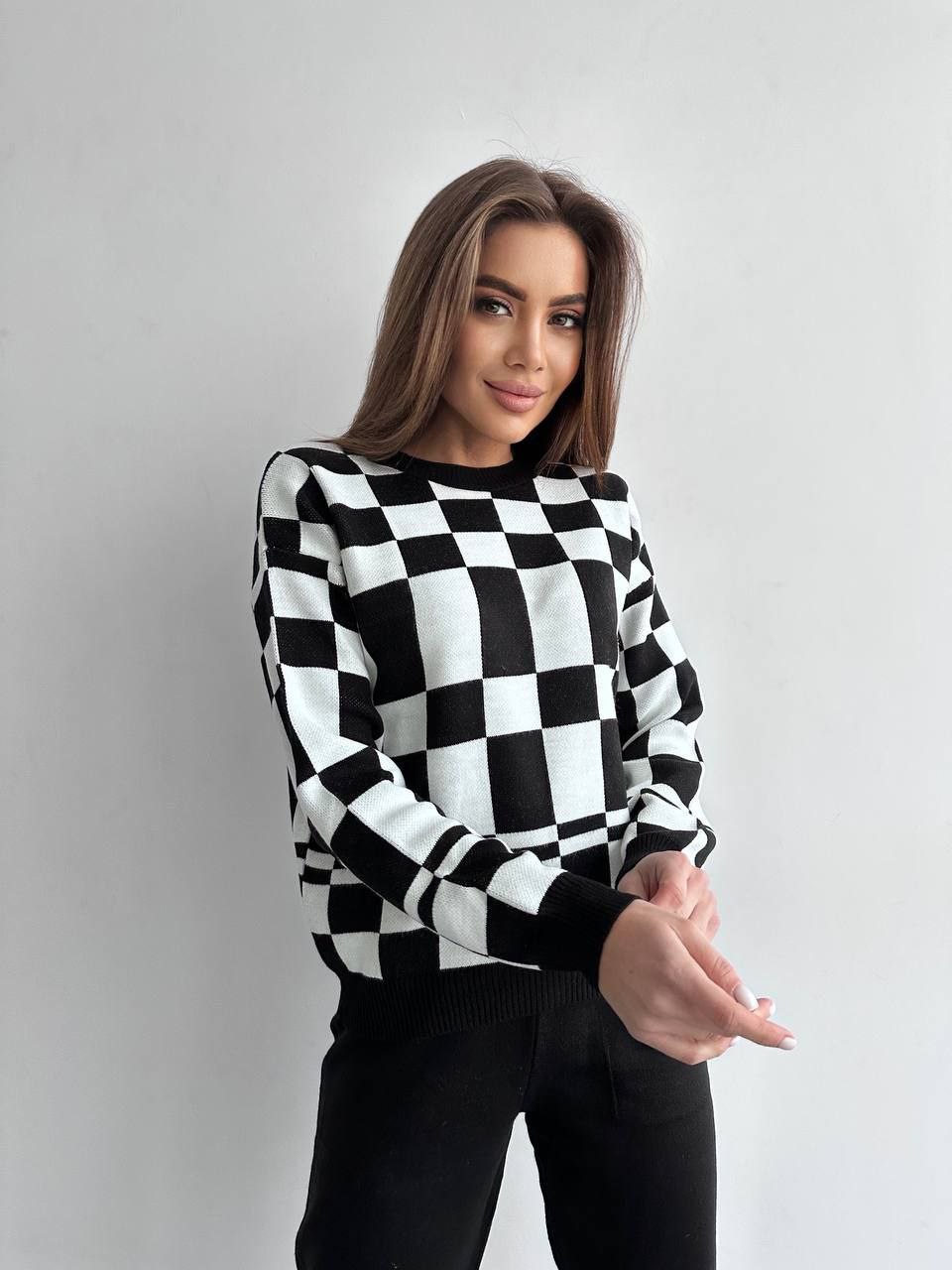 Woman wearing a black and white checkered sweater on a gray background