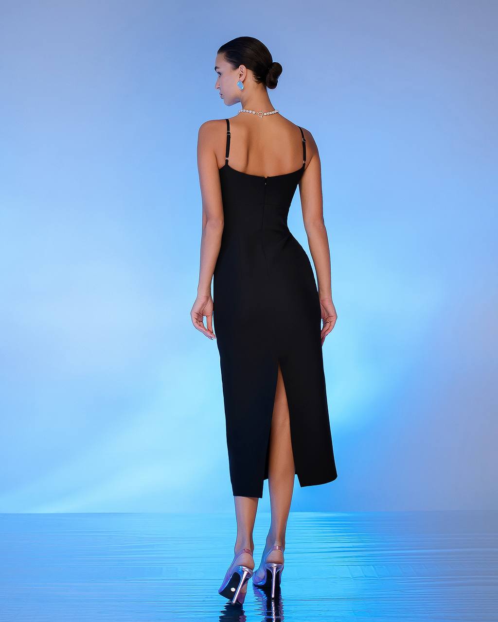 Woman wearing a black dress with a high slit on a blue gradient background