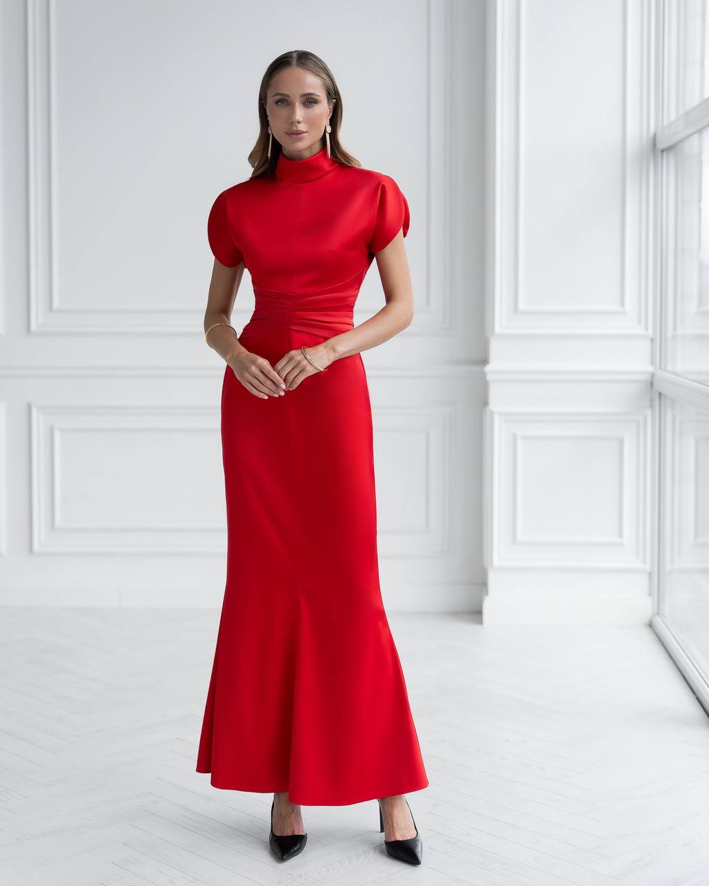Woman wearing a red dress against a white wall