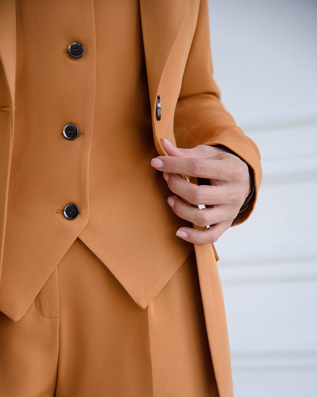 Close-up of a person wearing a brown coat with buttons, holding their hand.