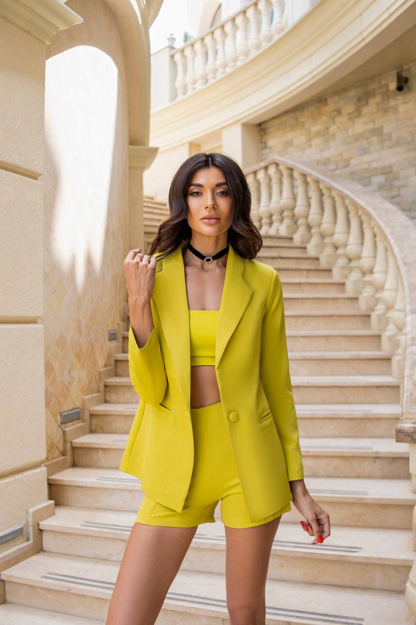 Woman in a bright yellow outfit standing on a staircase with architectural background