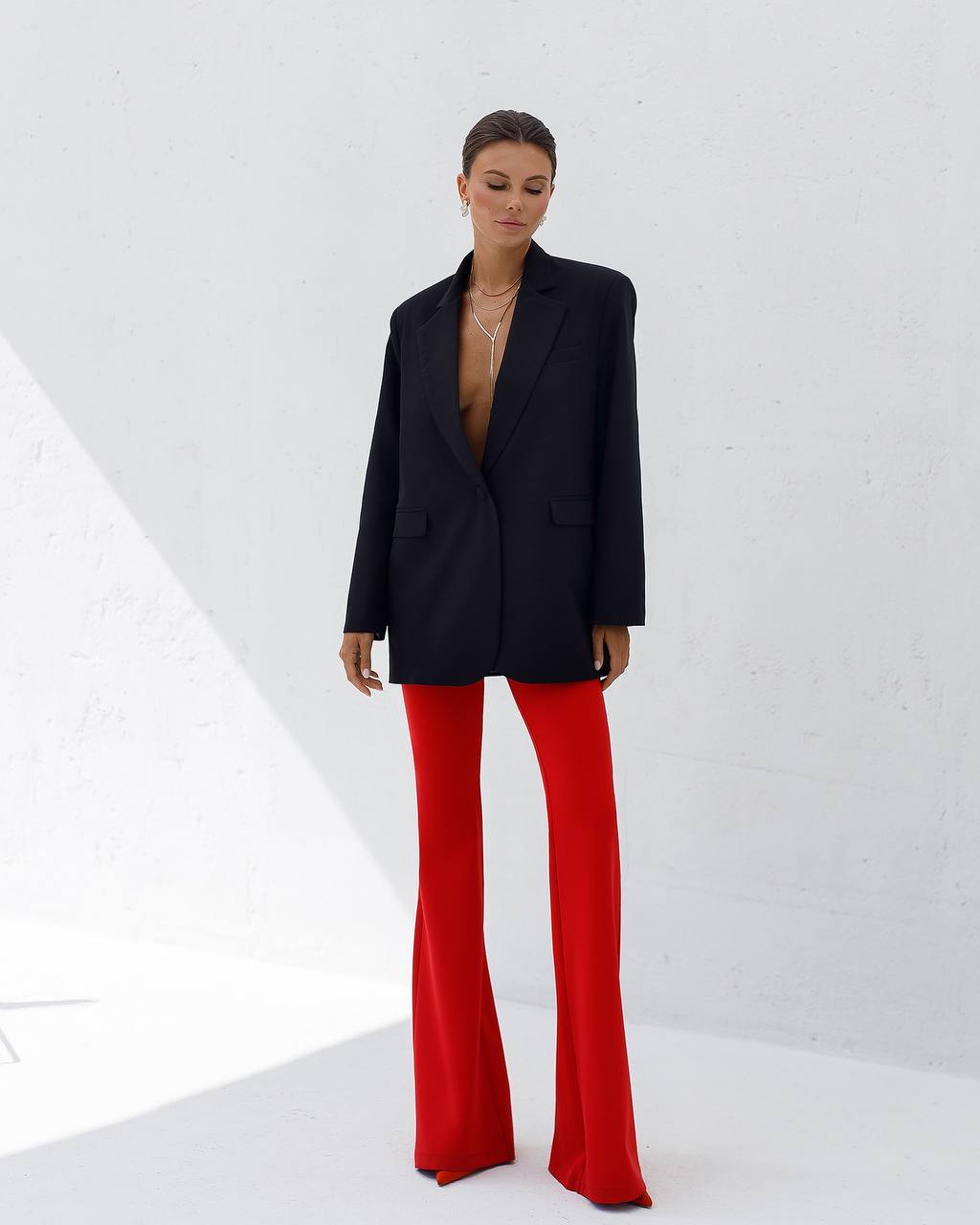 Person wearing a black blazer and red pants on a white background