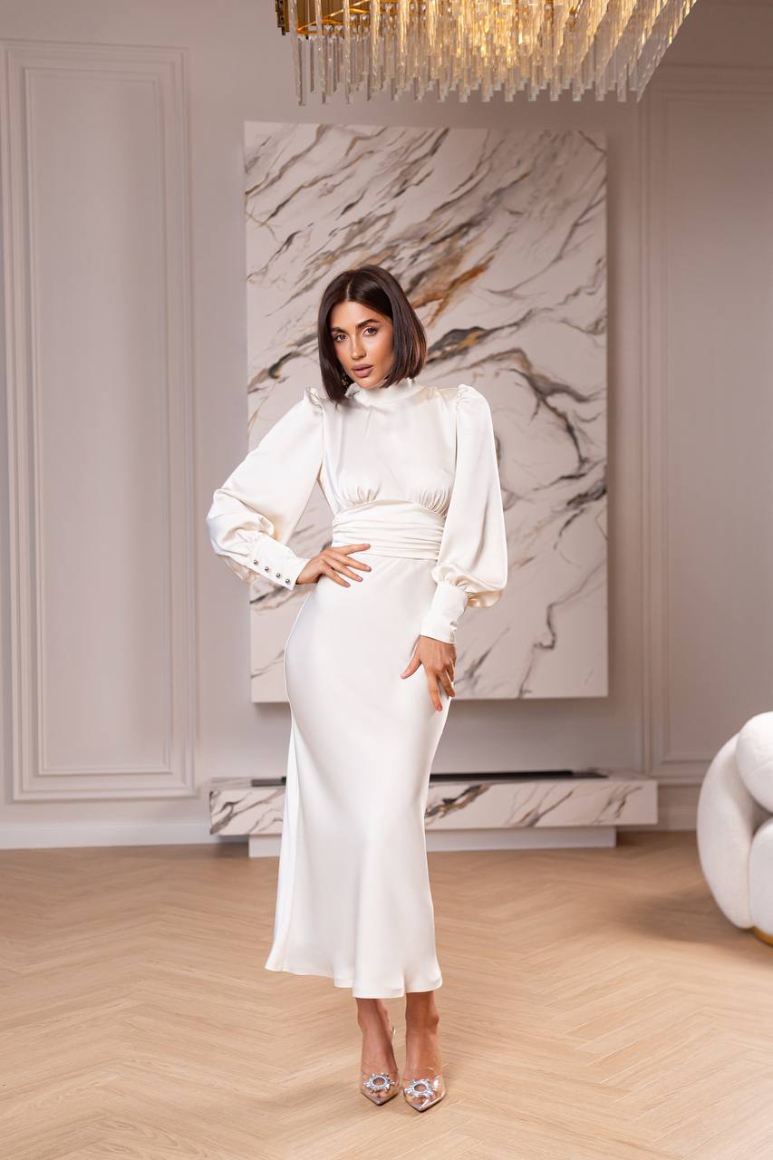 Woman in a white outfit standing in a stylish room with marble wall art.