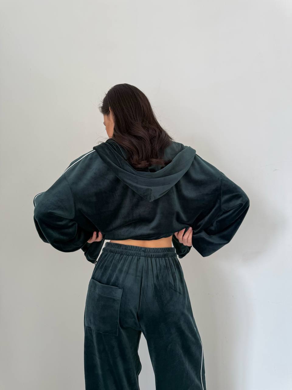 Person wearing a dark green hoodie and pants against a plain background
