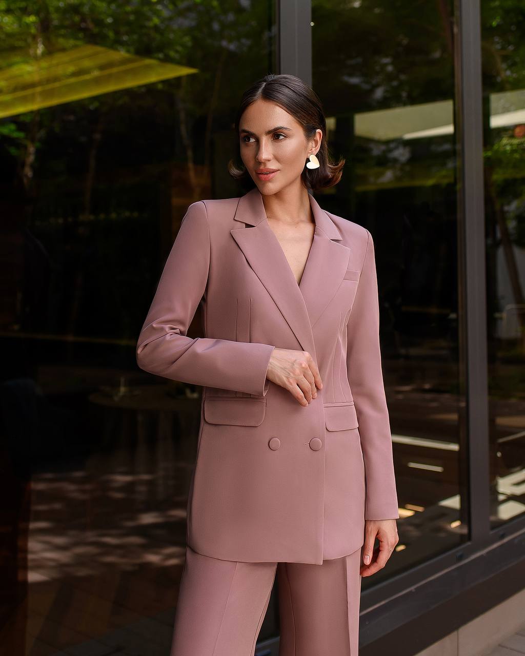 Woman in a pink suit standing outdoors with blurred background