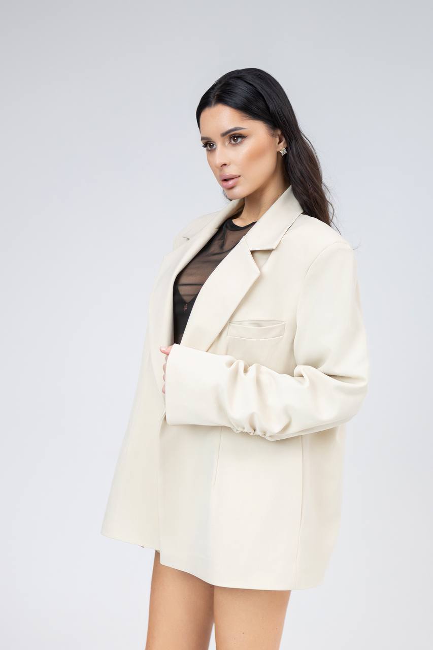 Woman wearing a cream blazer over a black top on a light gray background