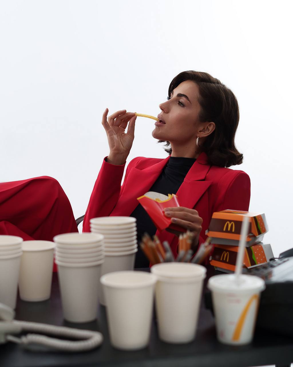 Woman in a red jacket eating McDonald's fries with a white background