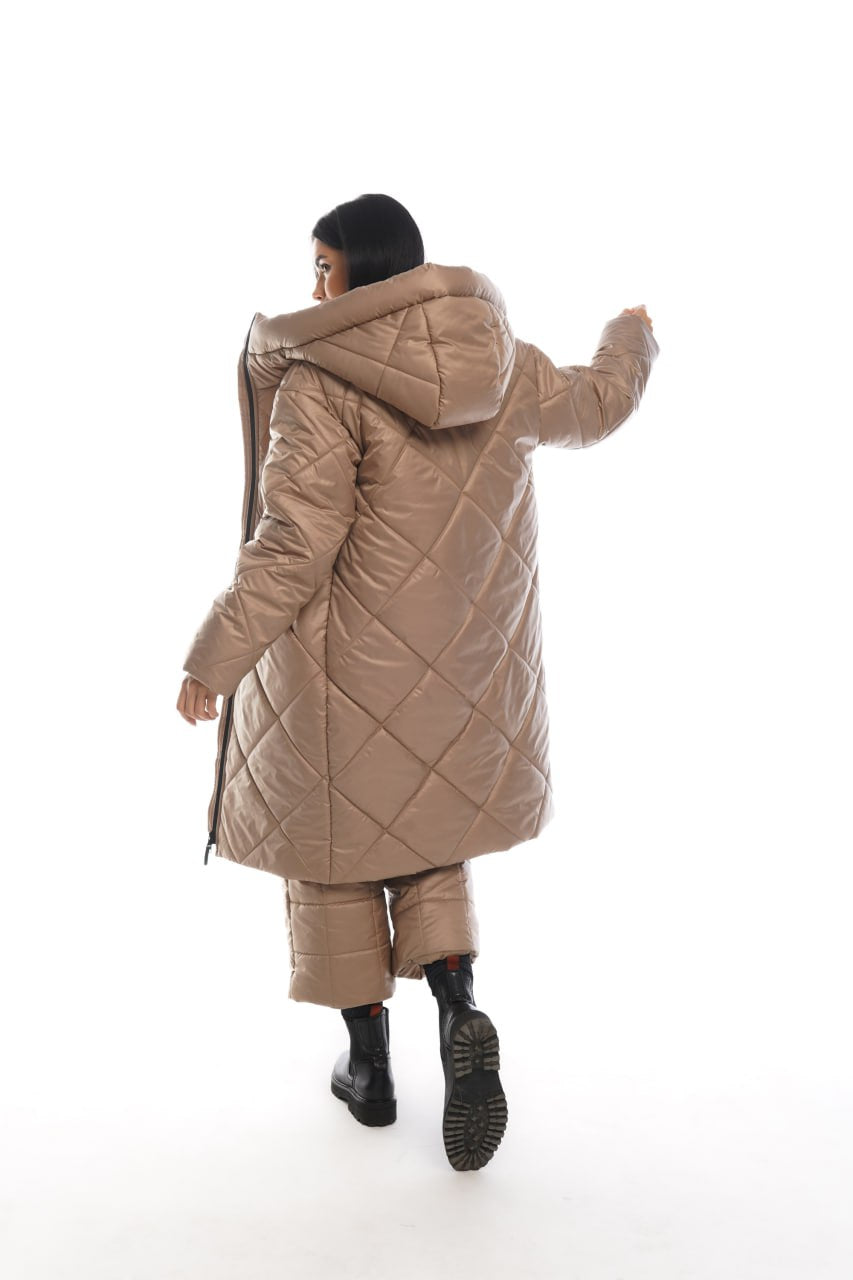 Person wearing a long quilted beige coat on a white background