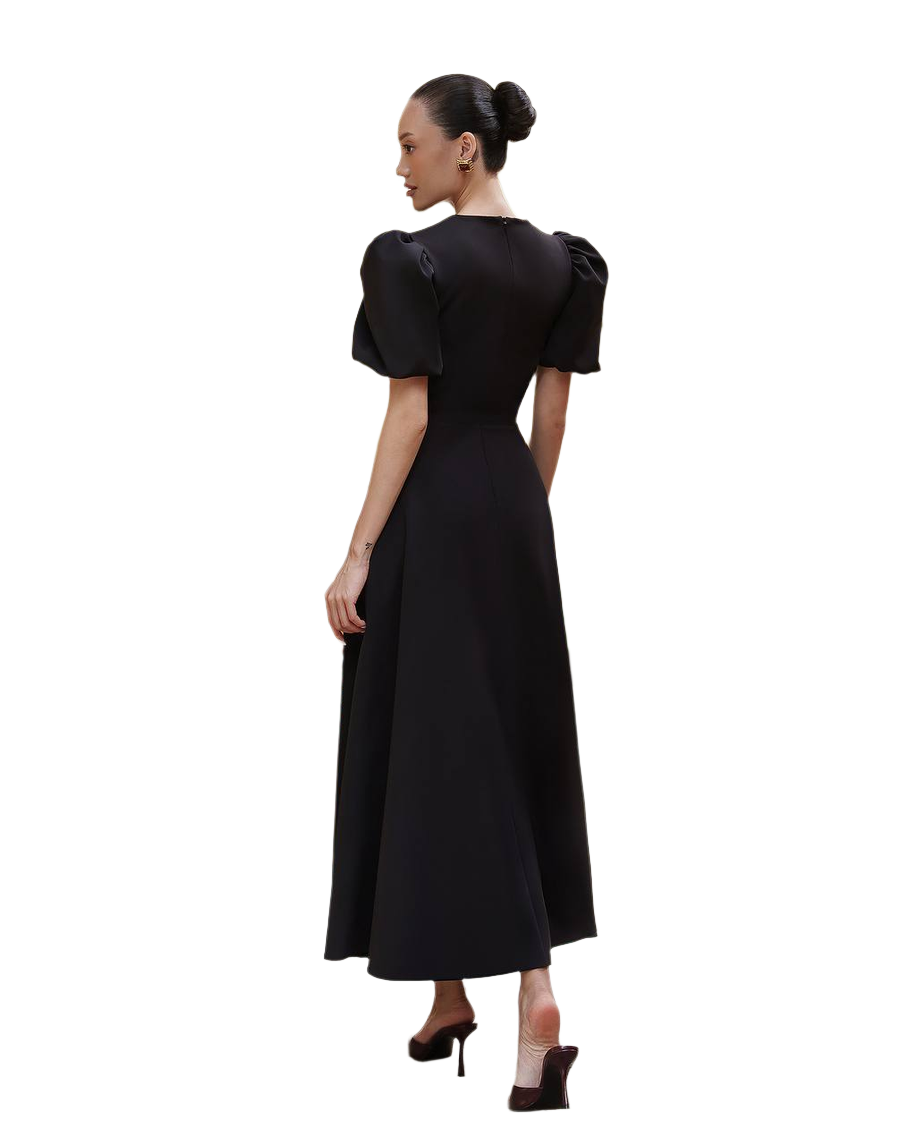 Woman wearing a black dress with puff sleeves on a white background