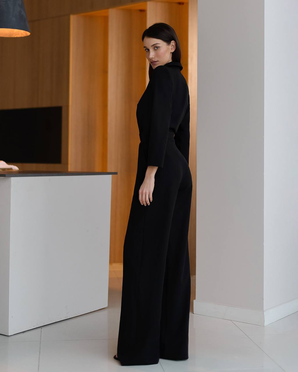 Woman in a black dress standing in an indoor setting with a modern design.