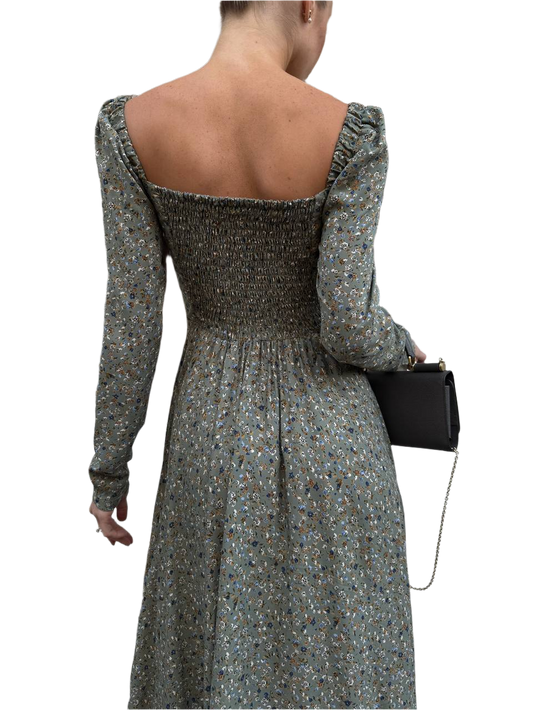 Woman wearing a floral dress with long sleeves and a black clutch on a white background