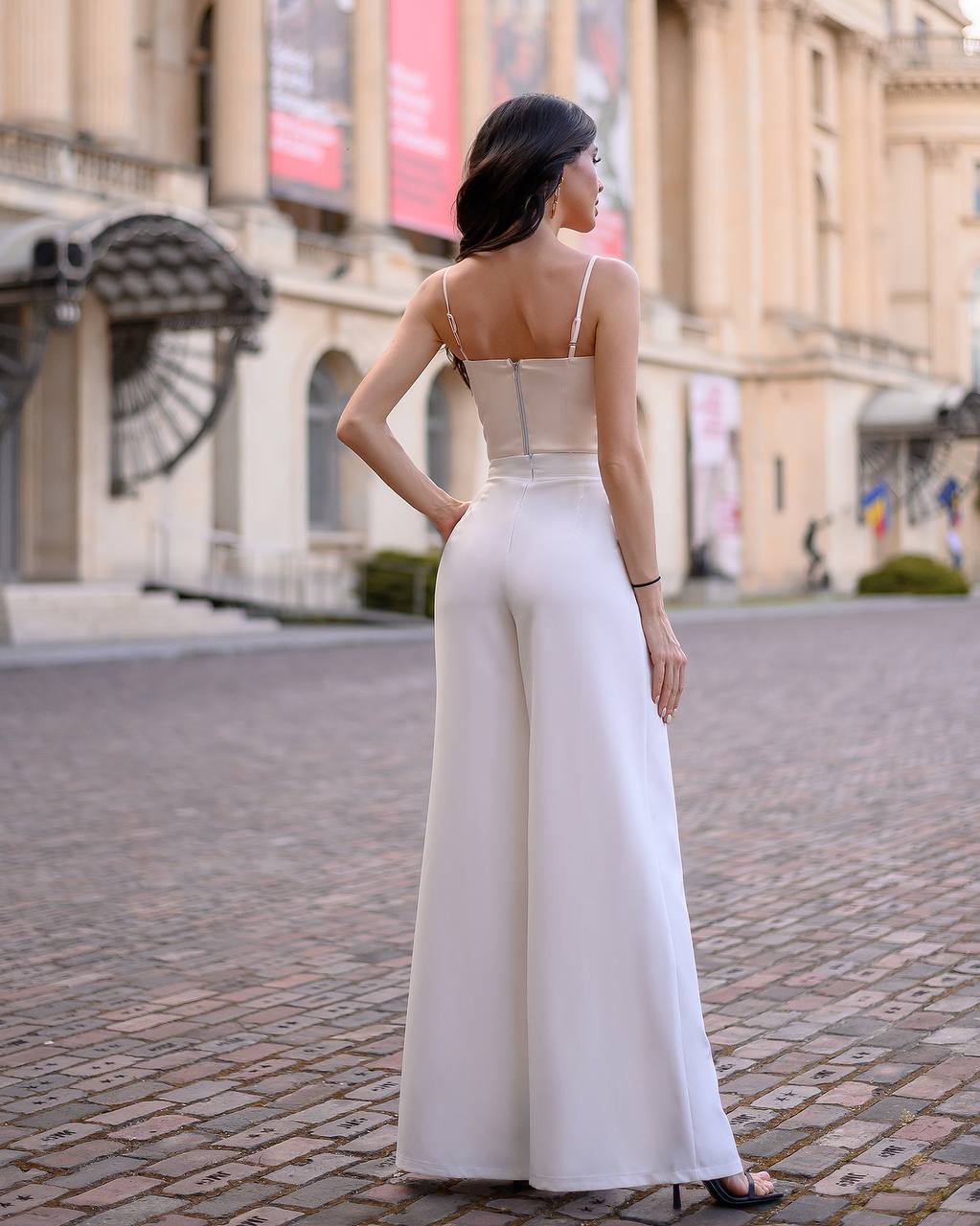 Woman in a white jumpsuit standing on a city street.