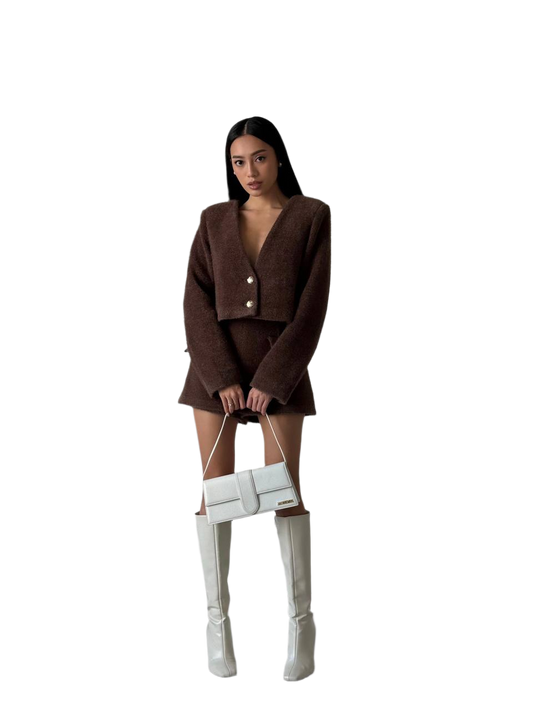Person wearing a brown outfit with a white handbag on a white background