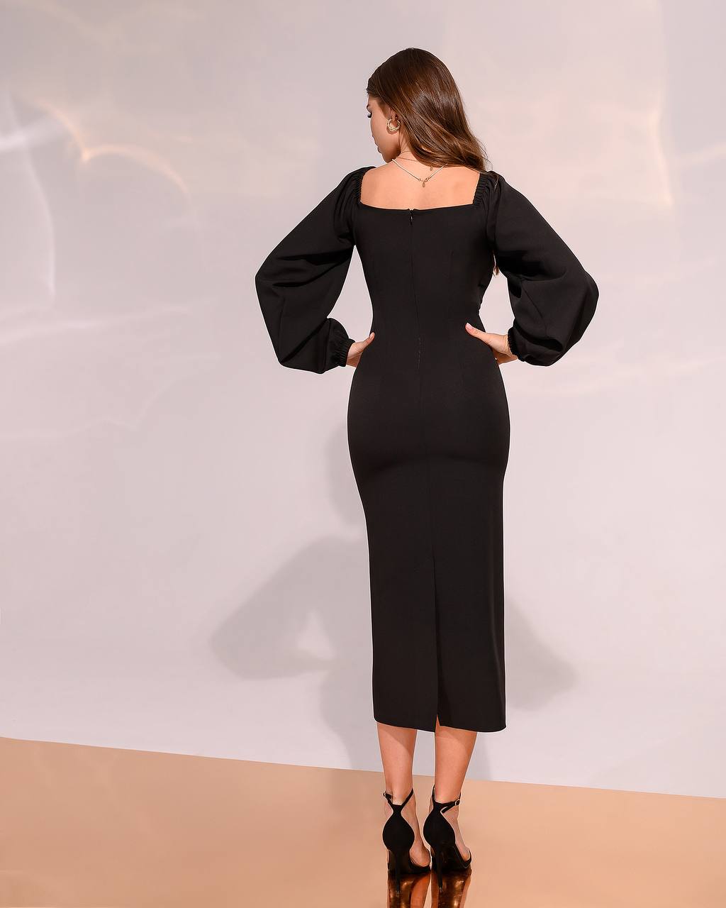 Woman wearing a black dress with puffed sleeves against a plain background