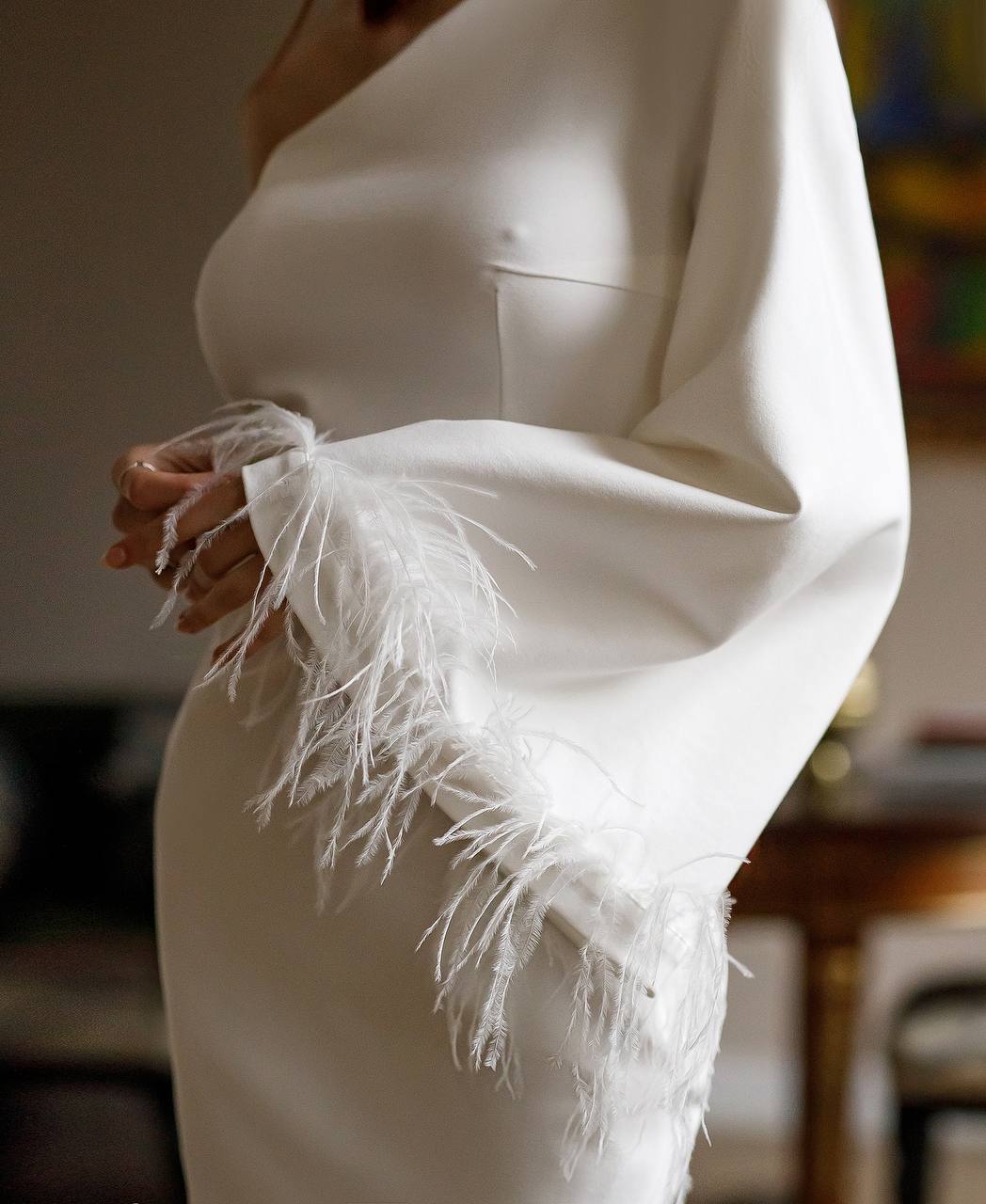 White dress with feathered sleeves on a blurred background