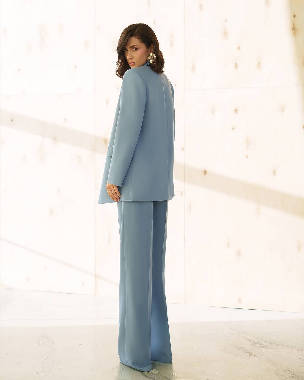 Woman wearing a light blue suit standing against a white background