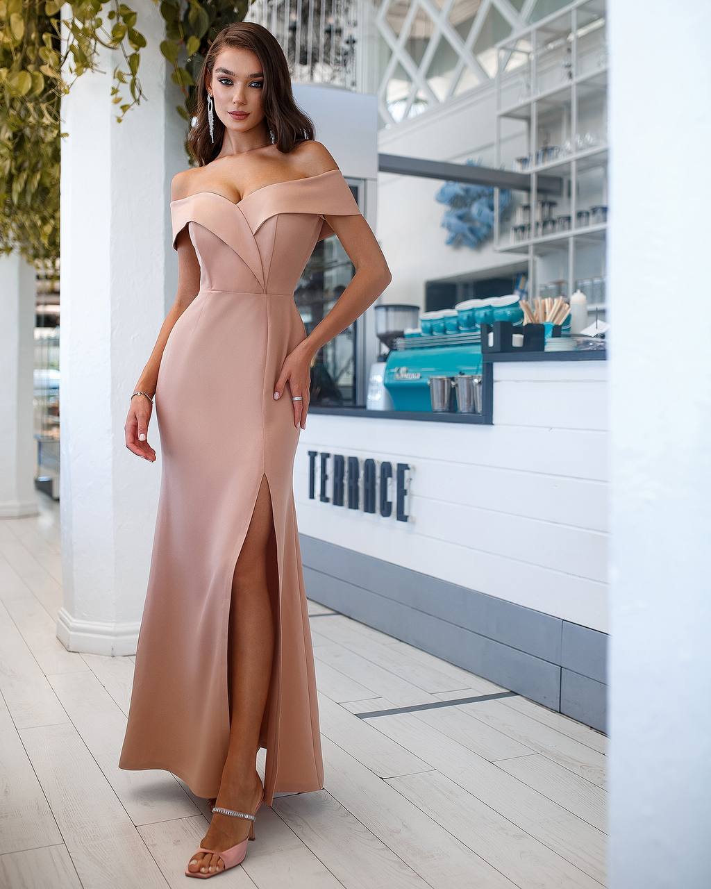Woman in a beige off-shoulder gown standing in a modern indoor setting with 'TERRACE' branding.