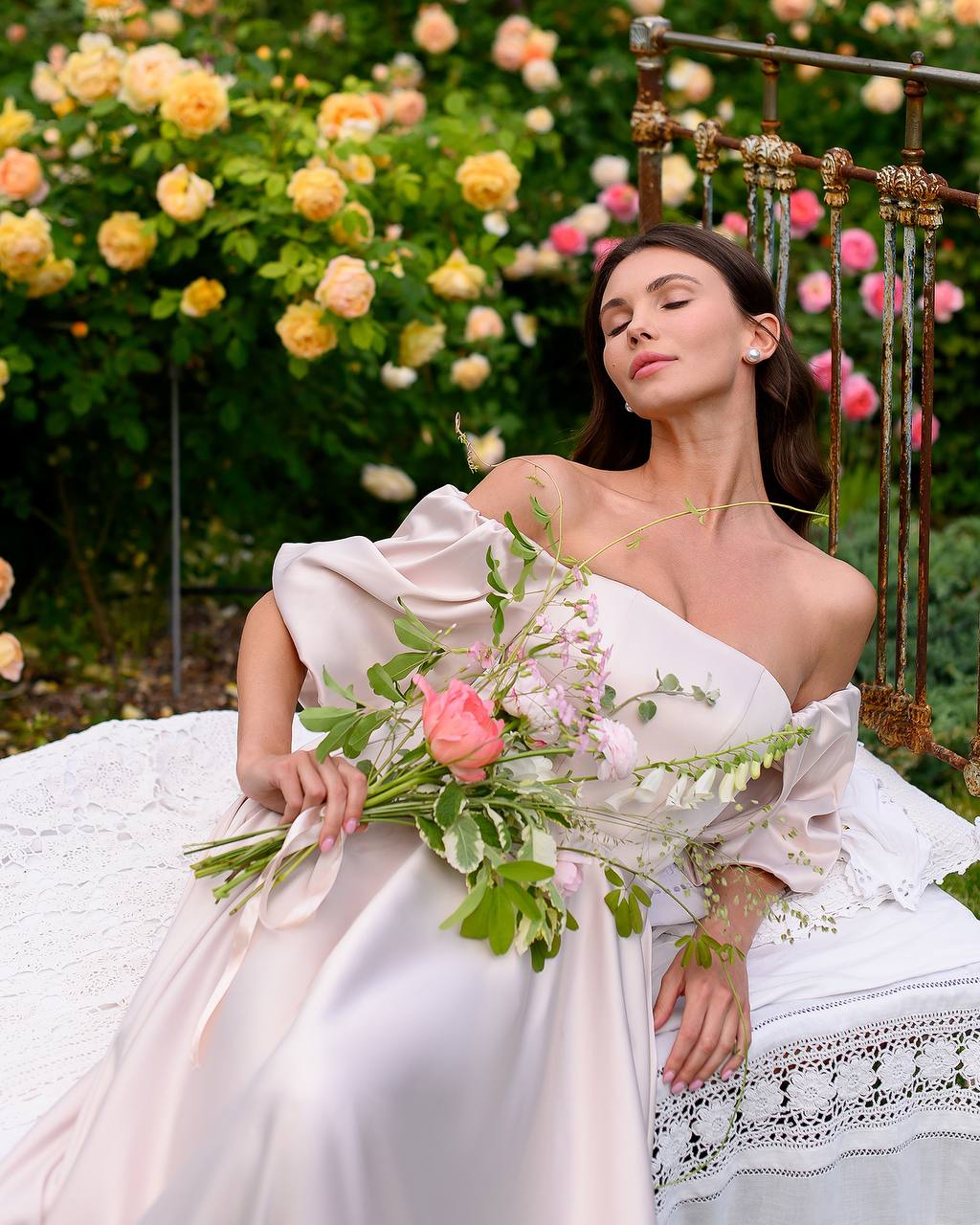 Woman in a white dress holding a bouquet of flowers in a garden setting