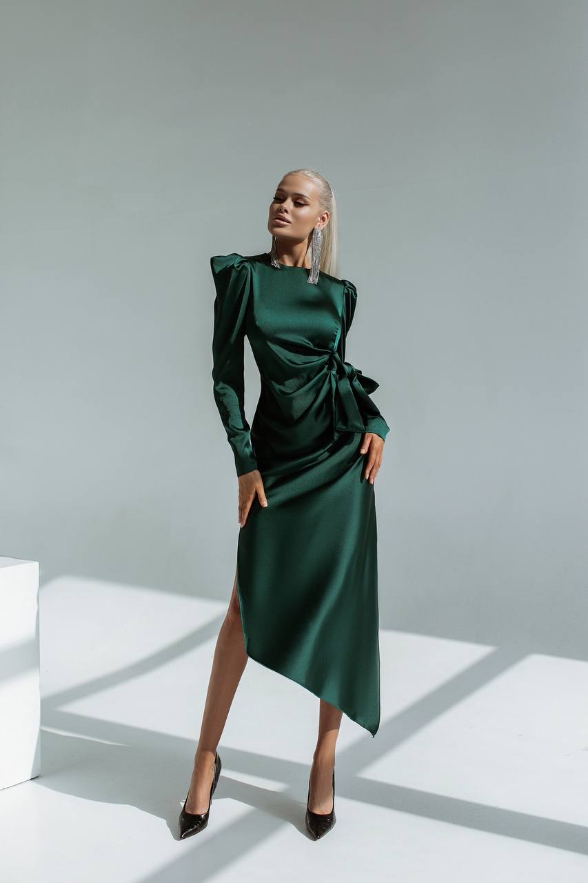Woman wearing a green dress with a high slit on a white background