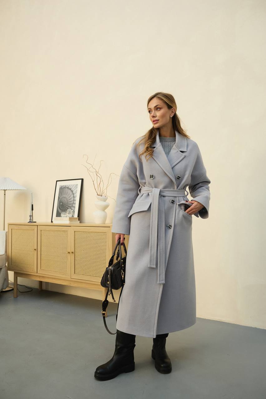 Woman wearing a long gray coat in an indoor setting