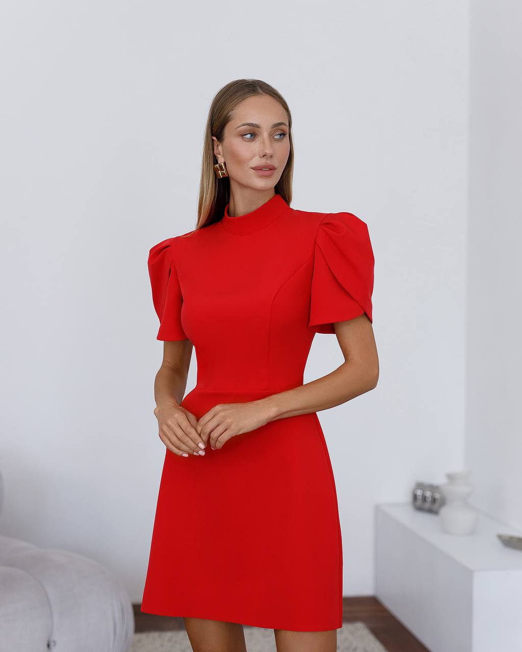 Woman wearing a red dress with puff sleeves in an indoor setting