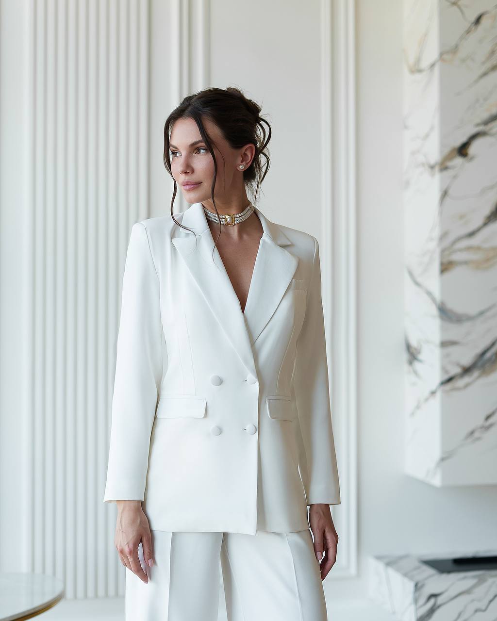 Woman wearing a white suit in a stylish interior setting