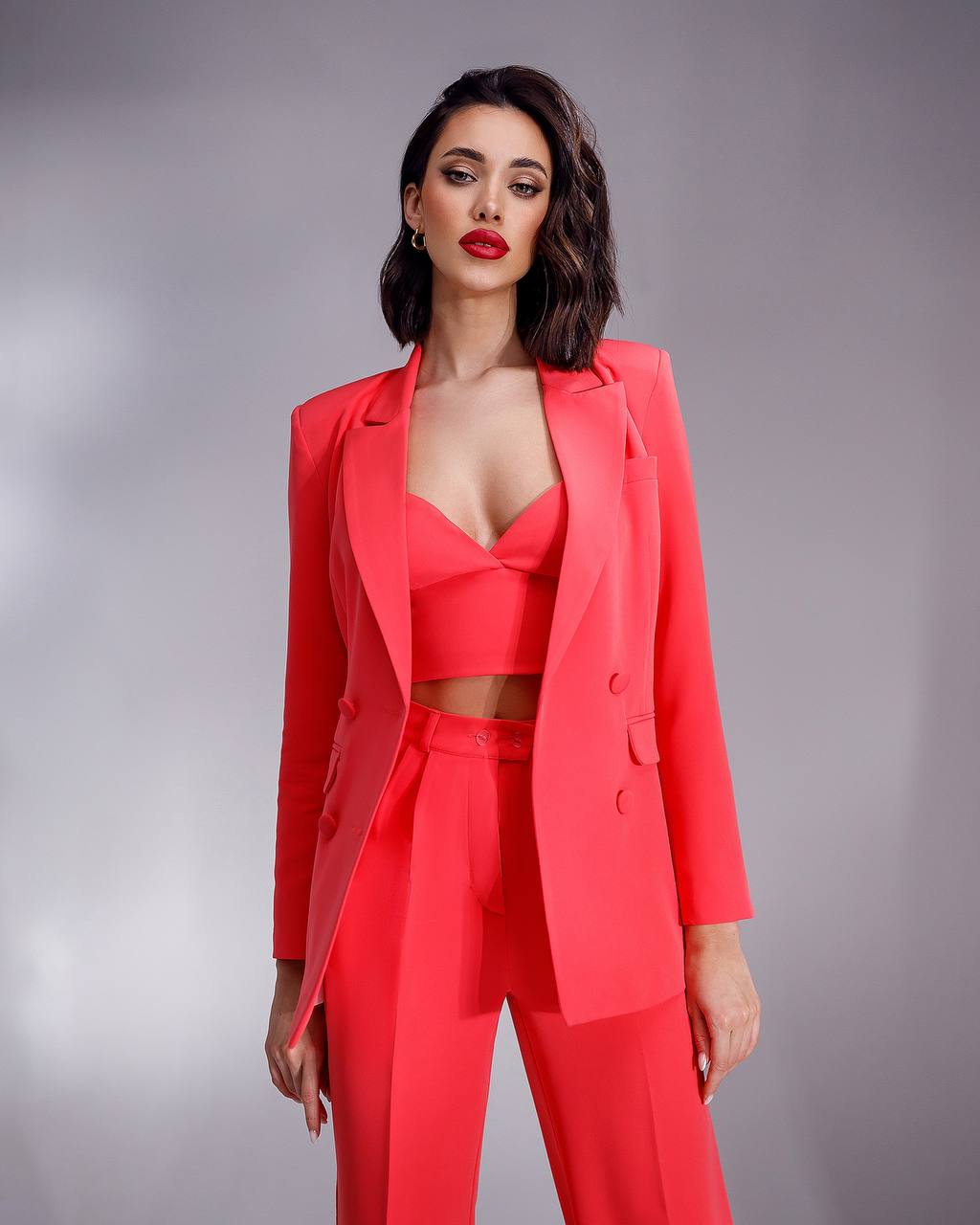 Woman wearing a red suit against a gray background