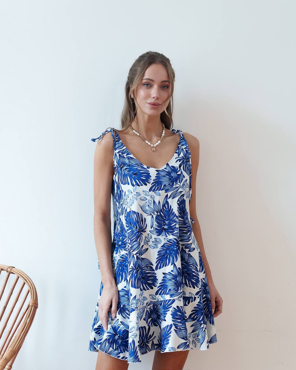 Woman wearing a blue and white floral dress against a plain background