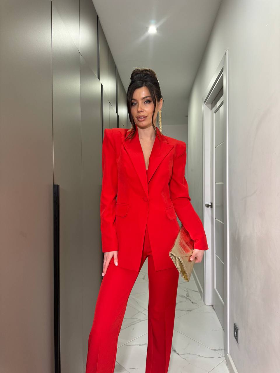 Person wearing a red suit standing in a hallway.