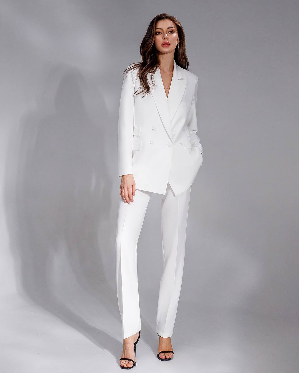 Woman wearing a white suit against a gray background