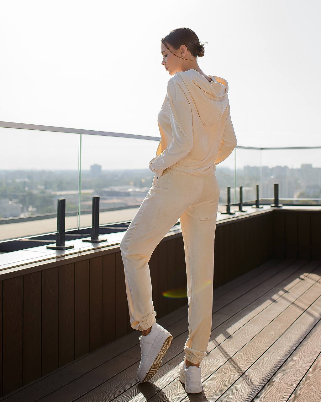Person in a white outfit standing on a rooftop with a cityscape view.