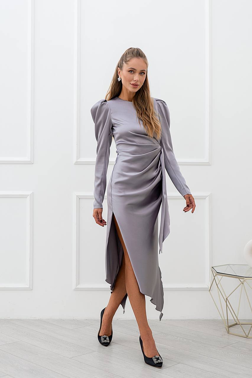Woman wearing a gray dress with long sleeves and a slit skirt in a minimalistic room.