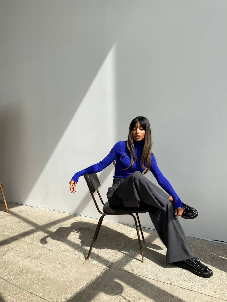 Person sitting on a chair against a gray wall with a spotlight effect.