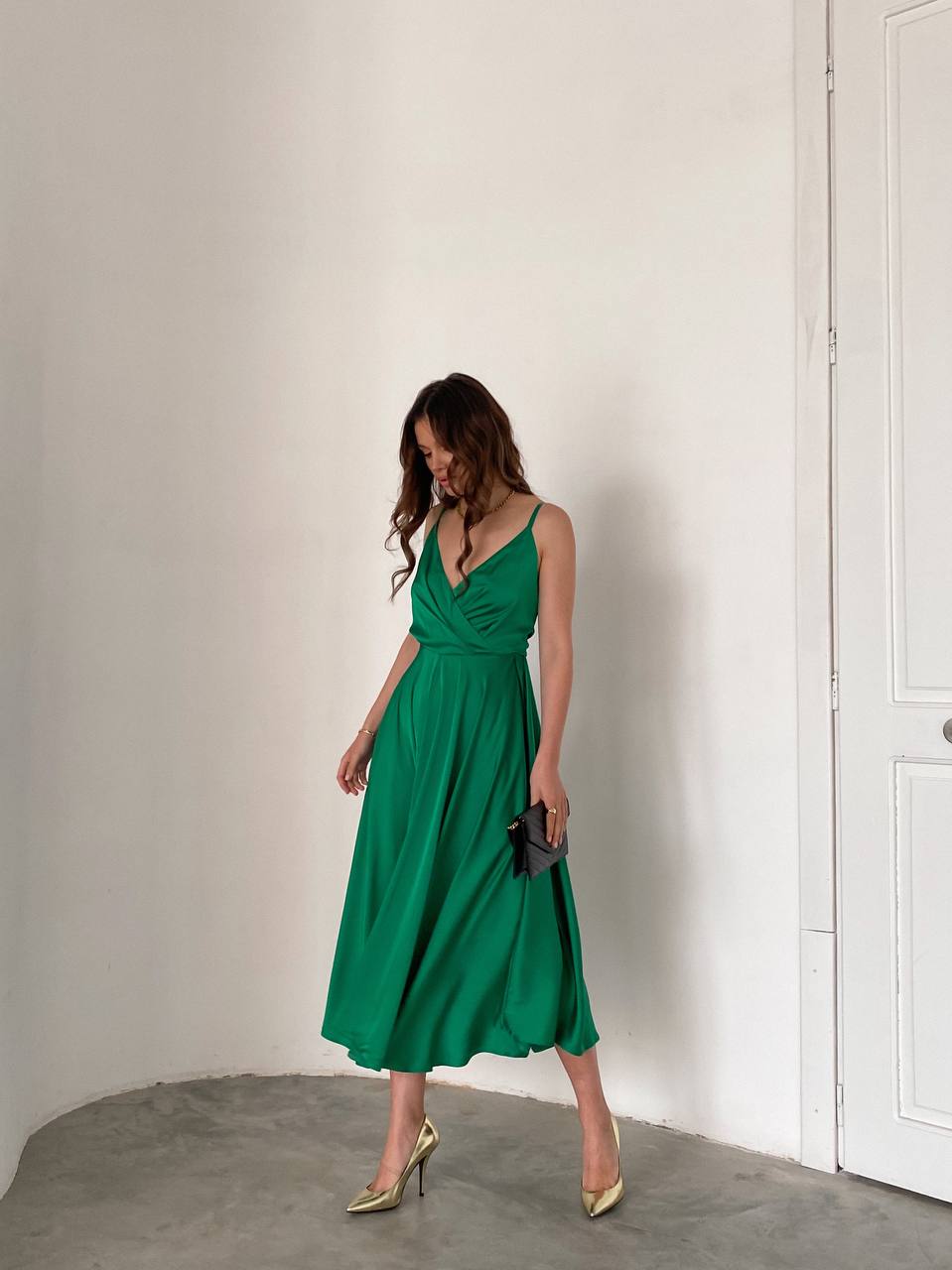 Woman wearing a green dress against a white wall