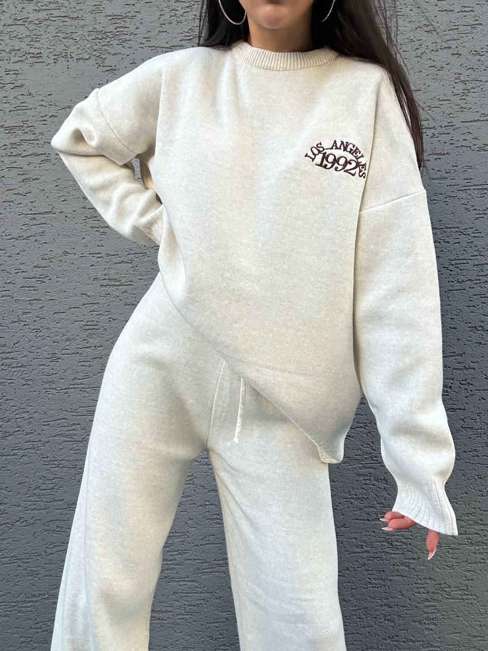 Person wearing a white sweatshirt and pants set with text on a gray background