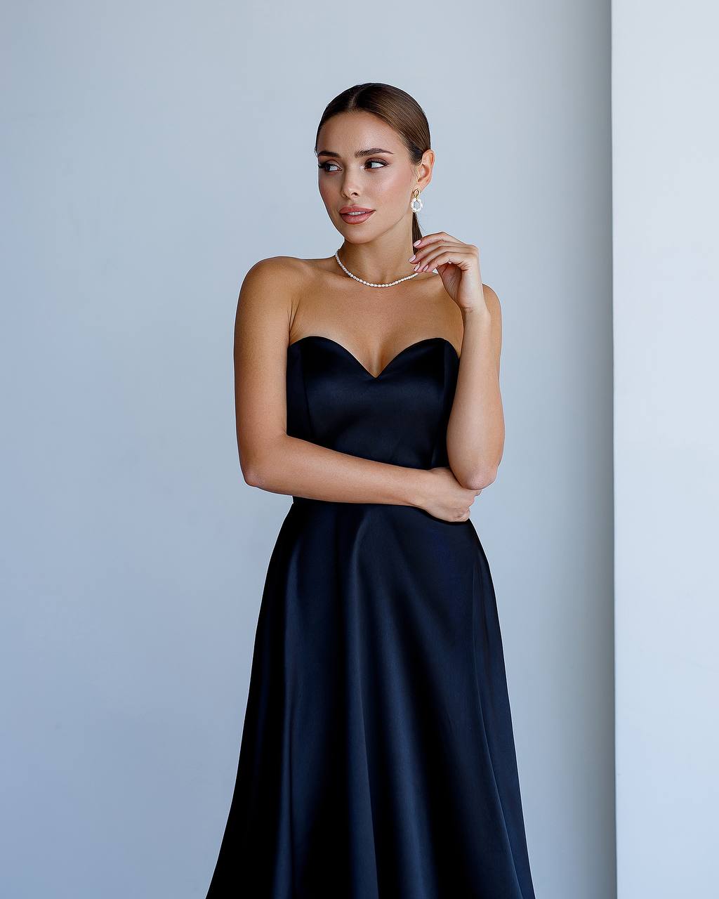 Woman wearing a black strapless gown against a plain background