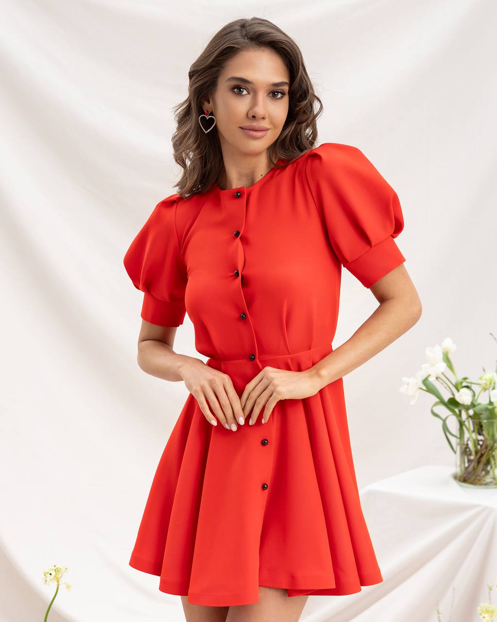 Woman wearing a red dress with black buttons on a white background