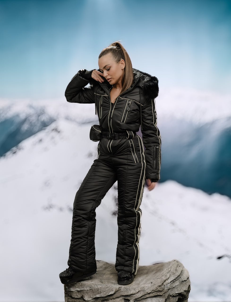 Person wearing a black snowsuit standing on a snowy mountain