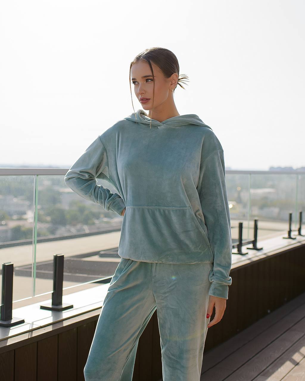 Woman wearing a light blue tracksuit on a rooftop with a cityscape background