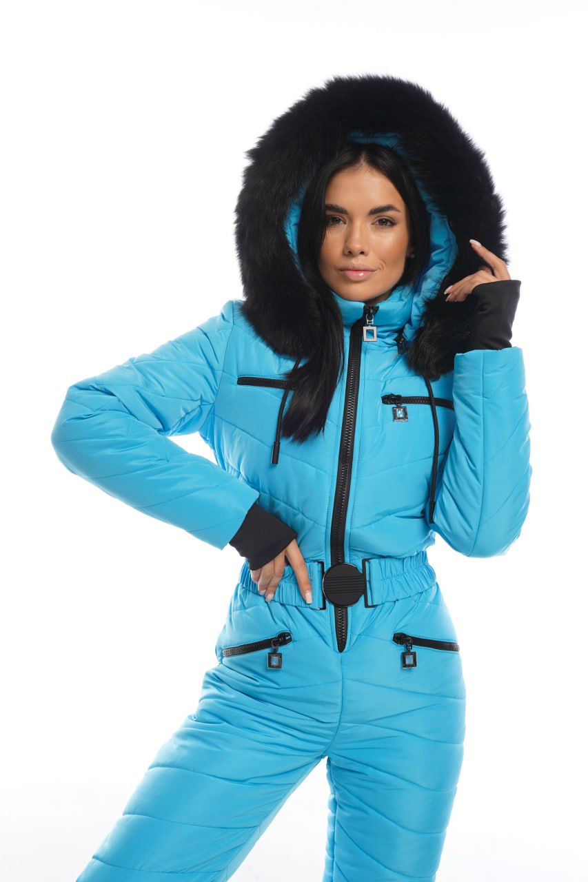 Woman wearing a blue snowsuit with black fur hood on a white background