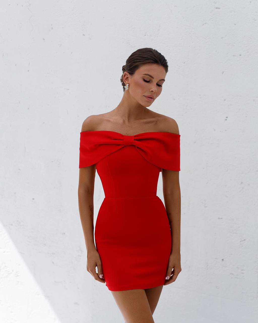 Woman wearing a red off-shoulder dress against a white background