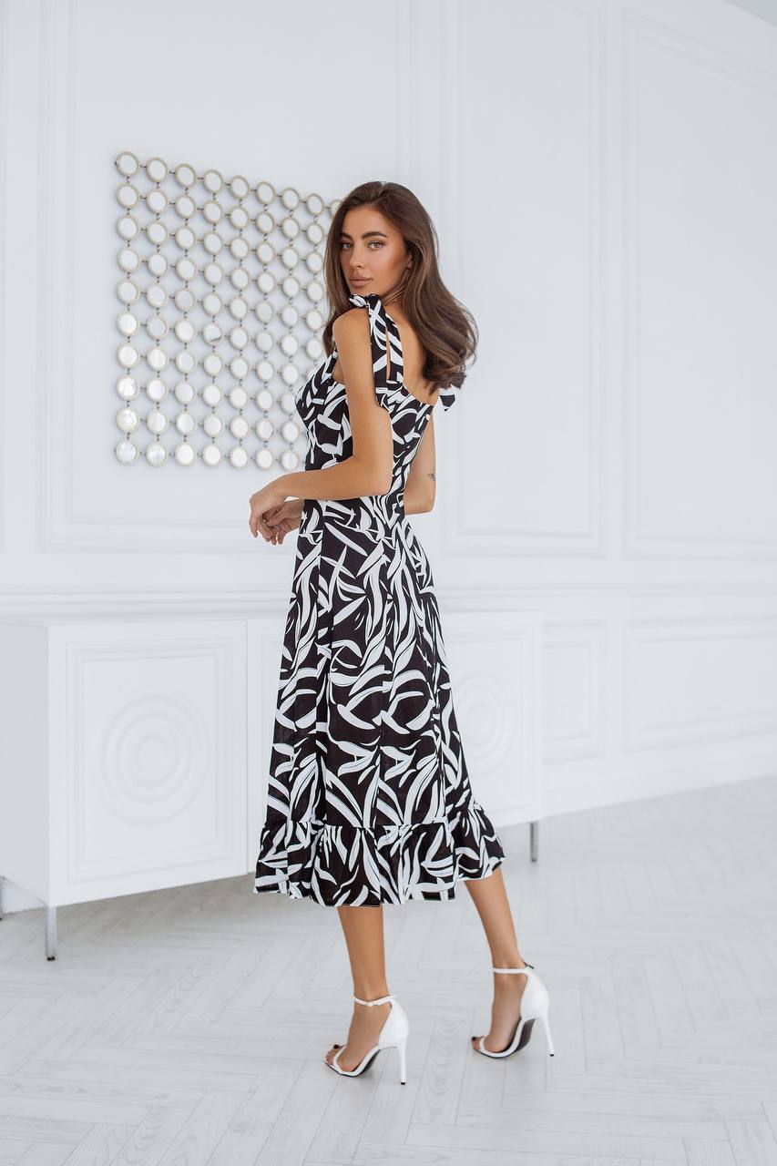Woman wearing a black and white patterned dress in a minimalistic room.
